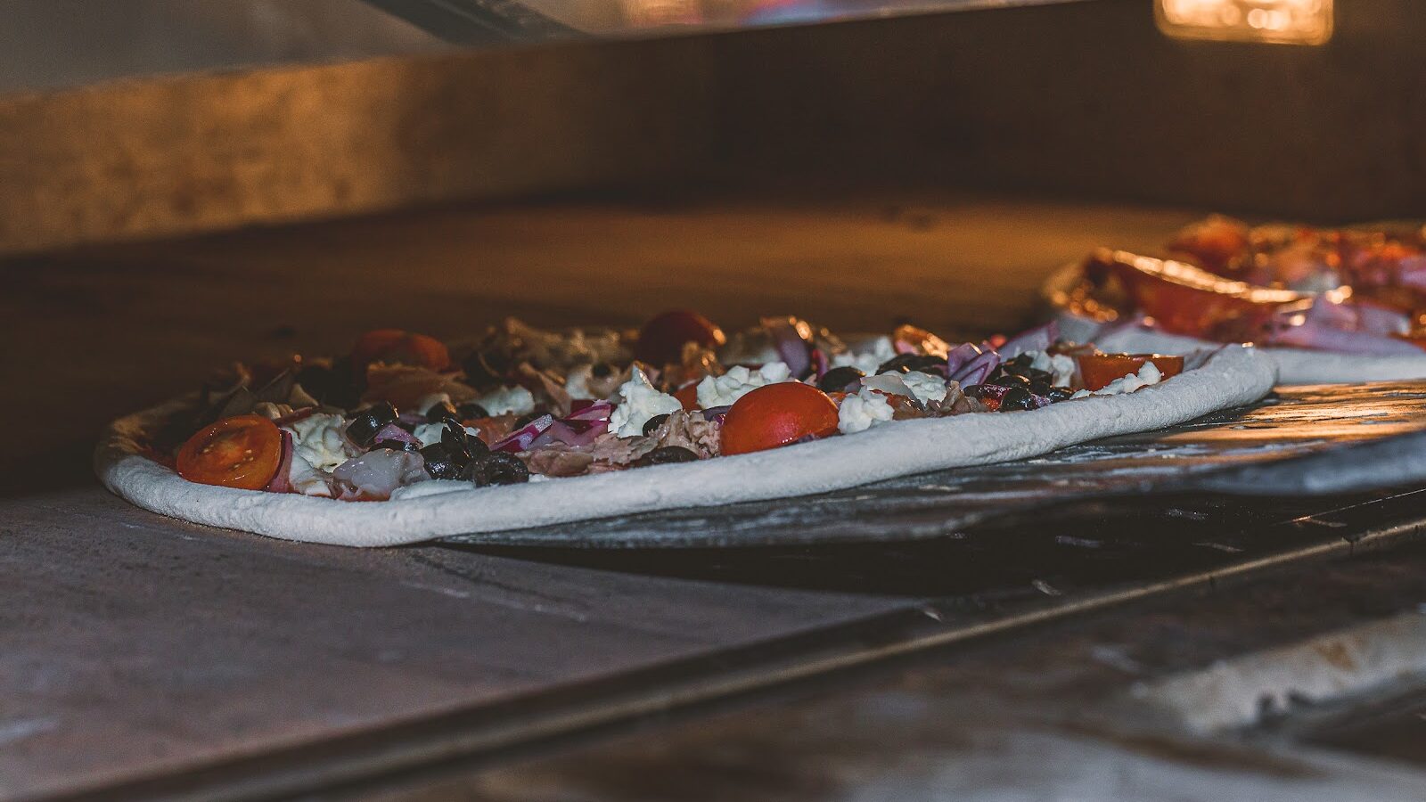 Pizza entrando en el horno de piedra de Pizzería Tellaro, en Castelló de la Plana