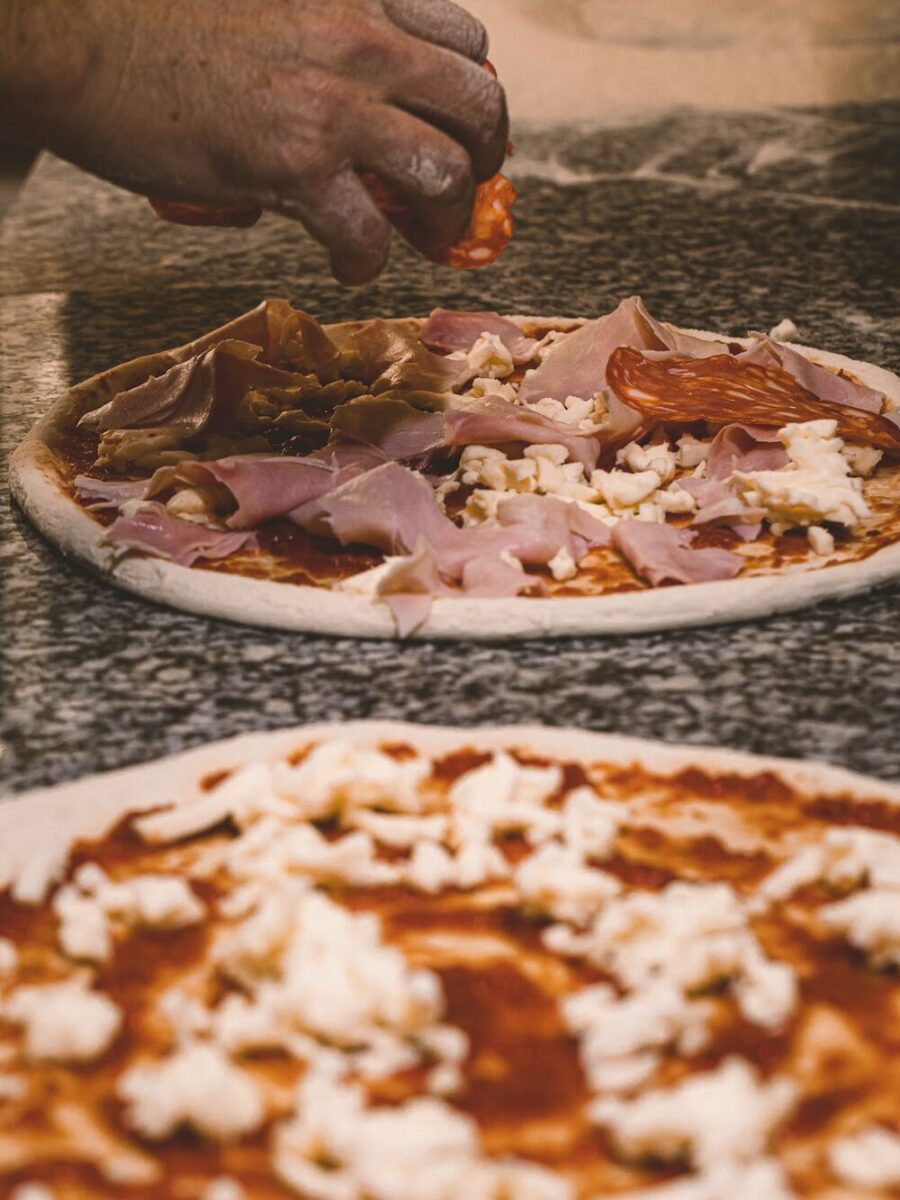 Las manos del pizzero montando dos pizzas en el obrador de Pizzería Tellaro
