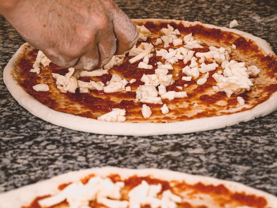 La mozzarella repartida a mano sobre la base con tomate